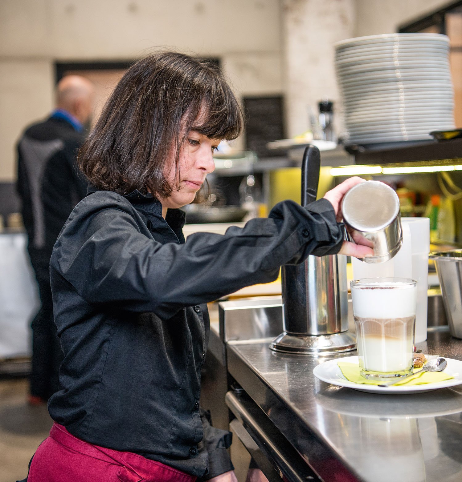 Eine Mitarbeiterin im Kunst-Cafe der Vorwerker Diakonie bereitet einen Latte Macchiato zu.