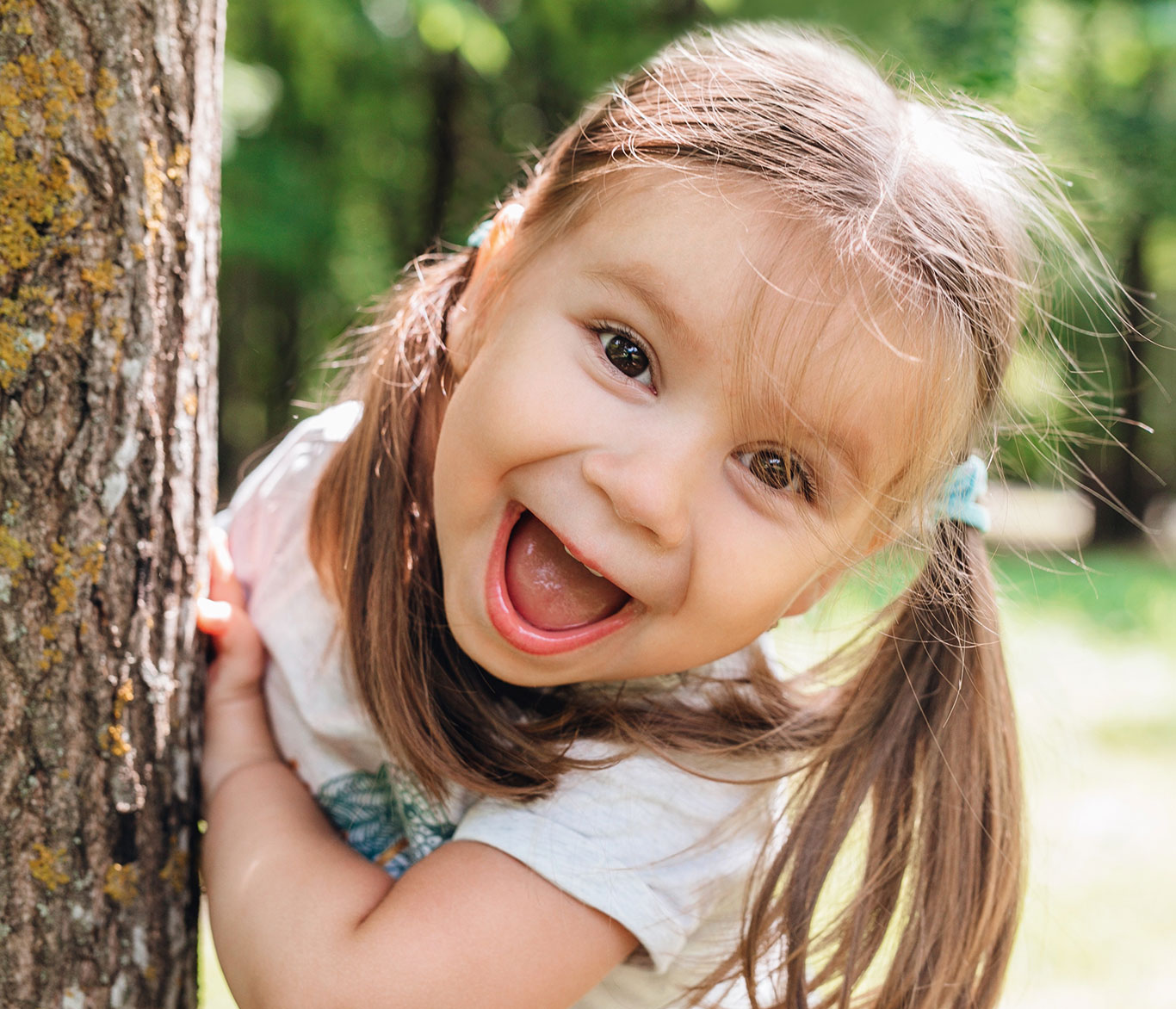 Ein Kind aus der Kindertagespflege spielt draußen und lächelt.