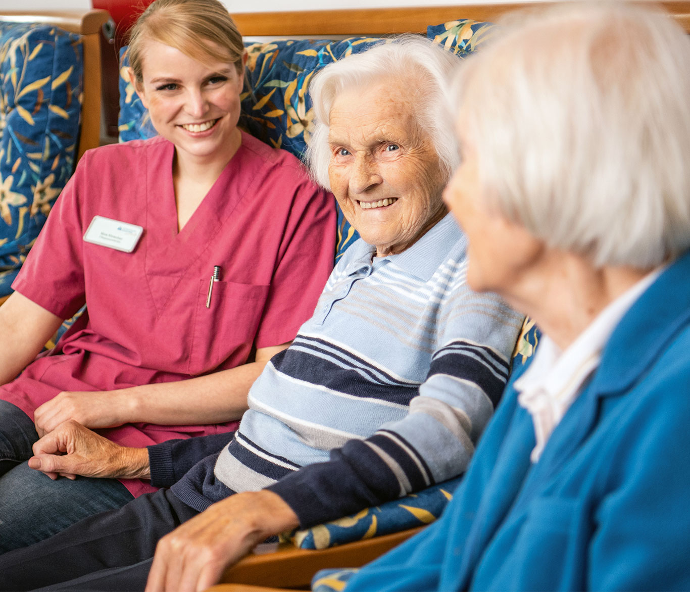 Pflegerin lacht mit zwei Seniorinnen in der Einrichtung der Seniorenpflege An der Georgskapelle in Bad Schwartau.