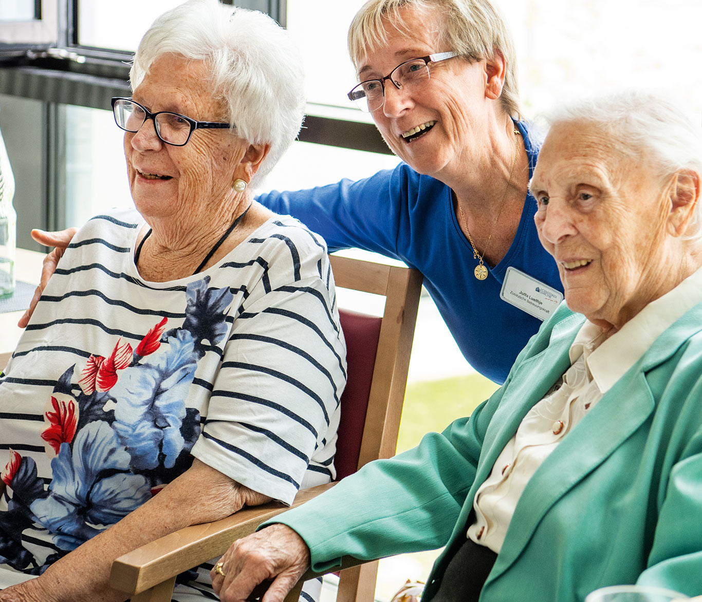 Eine Pflegerin stellt sich zu zwei Pflegebedürftigen in der Einrichtung der Seniorenpflege in Travemünde.