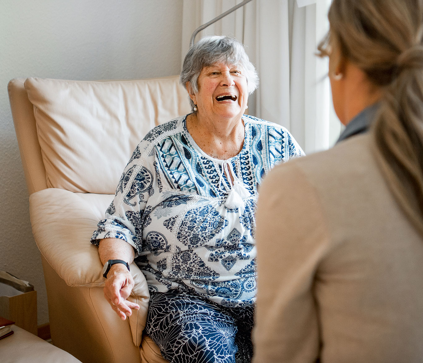 Eine pflegebedürftige Seniorin unterhält sich mit einer Pflegerin in einer Einrichtung der Seniorenpflege.