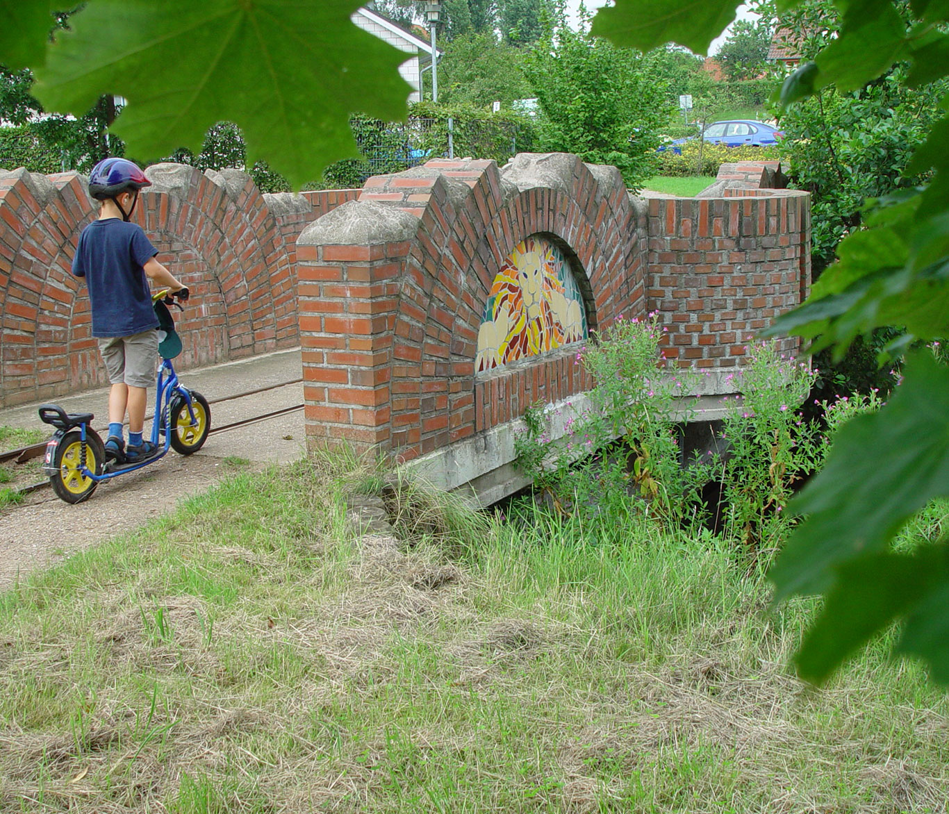 Ein Junge fährt mit einem Roller über eine Brücke im Bürgerpark der Vorwerker Diakonie.
